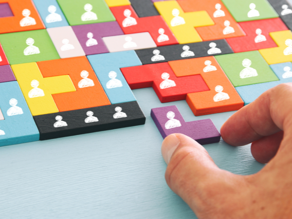 Person using colourful blocks with human silhouettes on them to fit into a jigsaw