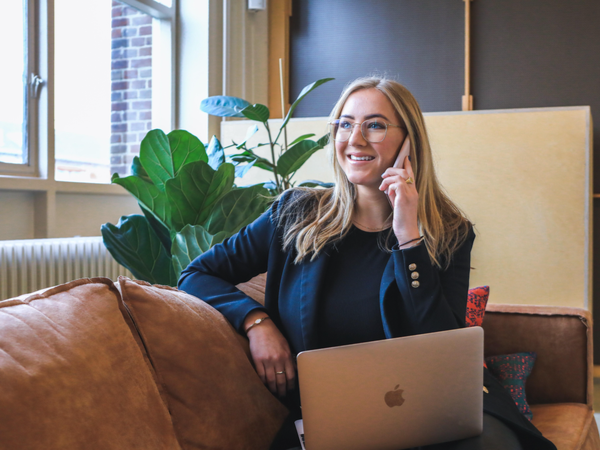 Woman smiling and on the phone with a laptop on her lap