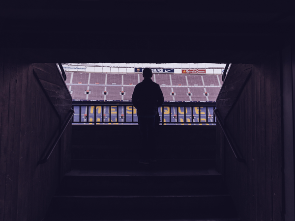 Silhouette of a person looking out into football stadium