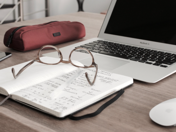 Laptop, glasses, notebook and pencil case on a desk