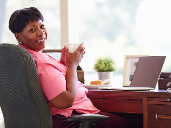 Middle-aged woman holding a hot drink by her desk