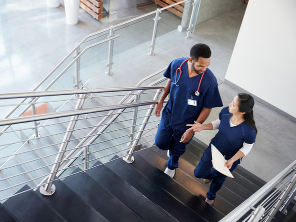 Two healthcare professionals talking as they walk up the stairs