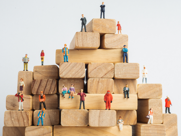 A tower of wooden playing blocks with small human figurines on them