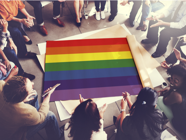 A group of people in a discussion around a Pride flag on the floor