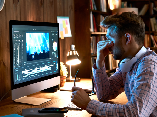 Person working at night looking stressed with their head in their hands