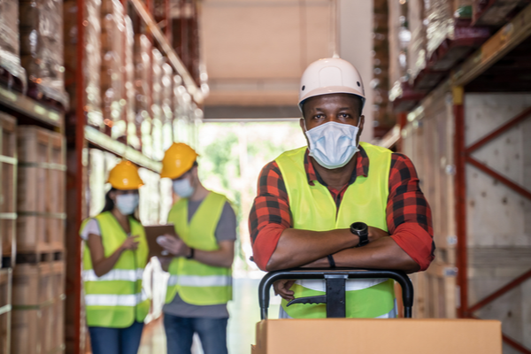 People with face masks, hard hats and high vis jackets on in the workplace