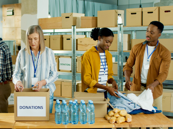 People working in a warehouse putting food and clothing donations in to boxes