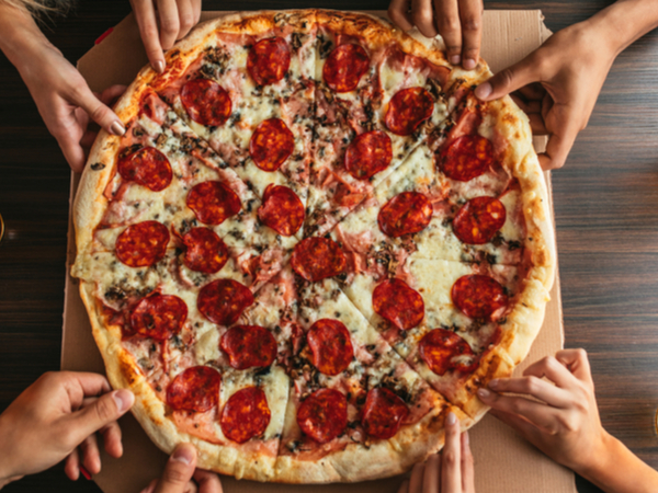 A group of people reaching for a slice of pizza