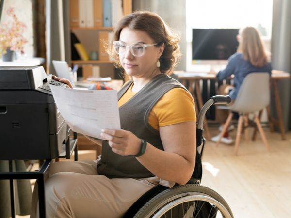 A woman in a wheelchair operates an office printer