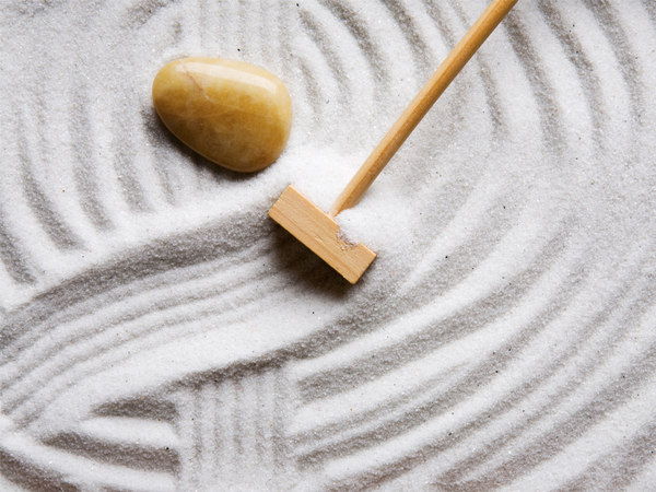 A small rake being raked through a Japanese zen garden