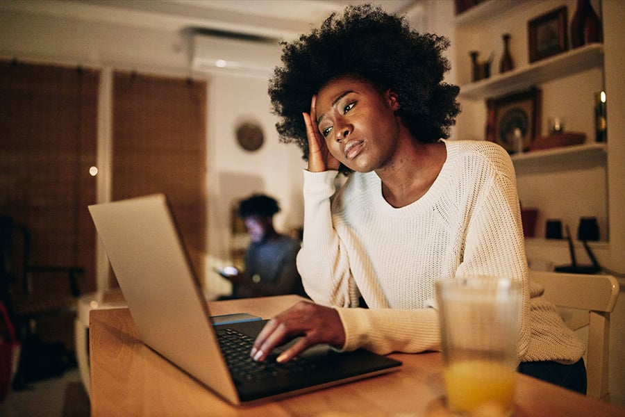 Woman working on a laptop, worn out and struggling with a problem