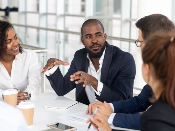 Man in suit explaining something to a group of businesspeople