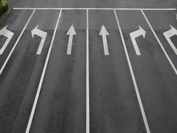 Six lanes on a highway with arrows pointing in different directions