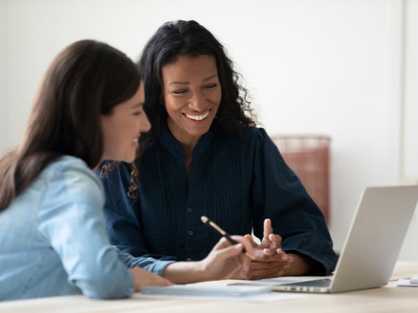 Two women working together in front of a laptop