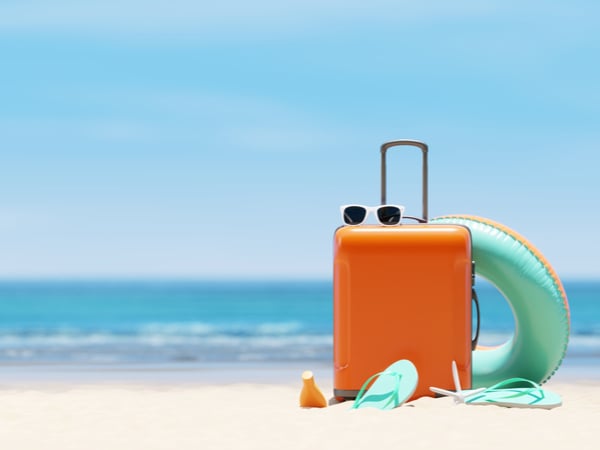 A suitcase on a beach with sunglasses and swimming accessories