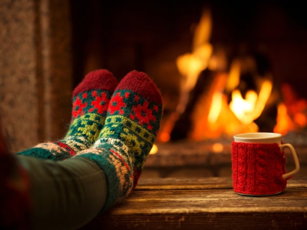 A person wearing woolly socks sitting in front of a roaring fire