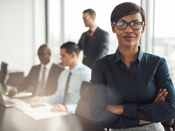 An image of a confident businesswoman with colleague working in the background