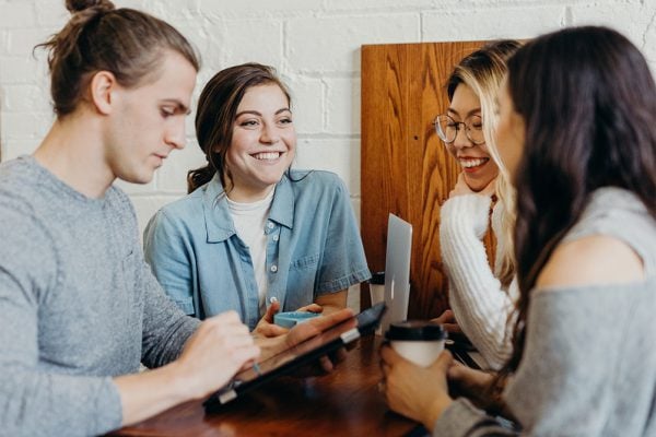 A group of young people around a table with drinks and devices