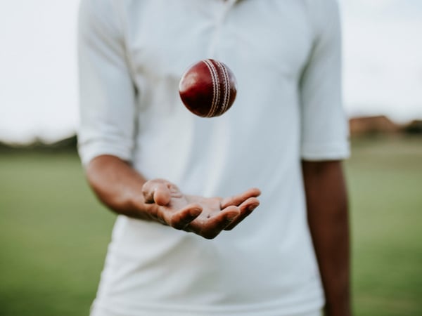 A cricketer throwing a cricket ball in the air