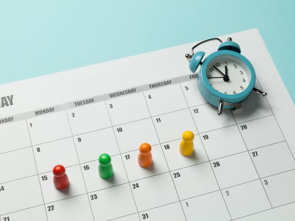 Four counters resting on four days of a calendar and an alarm clock