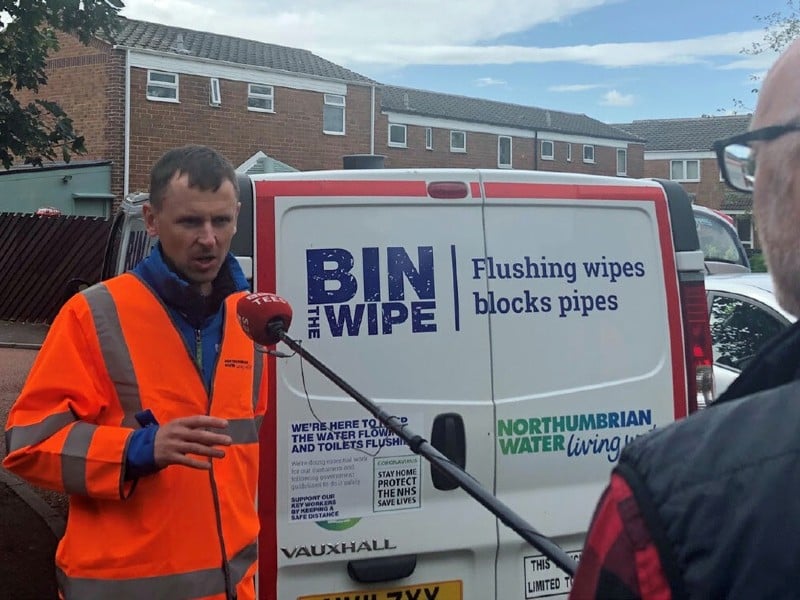A man in a high-vis jacket speaks to an interviewer in front of his van