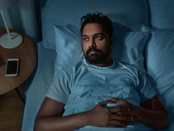 A man lying awake in bed at night