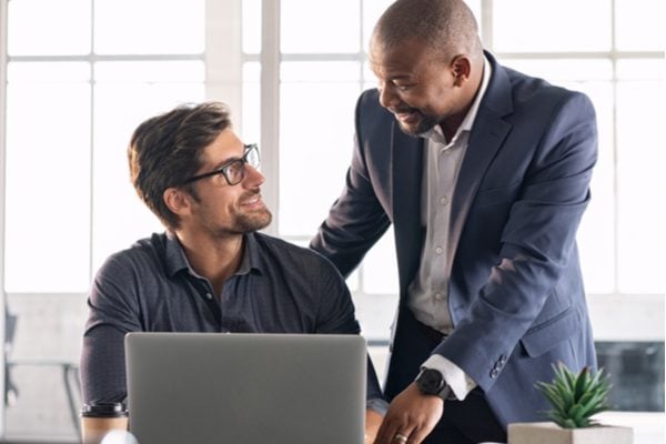 Two men from different ethnic backgrounds talking in front of a laptop