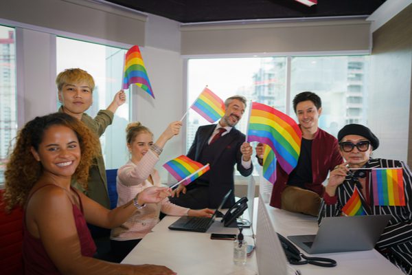 A group of colleagues holding rainbow flags