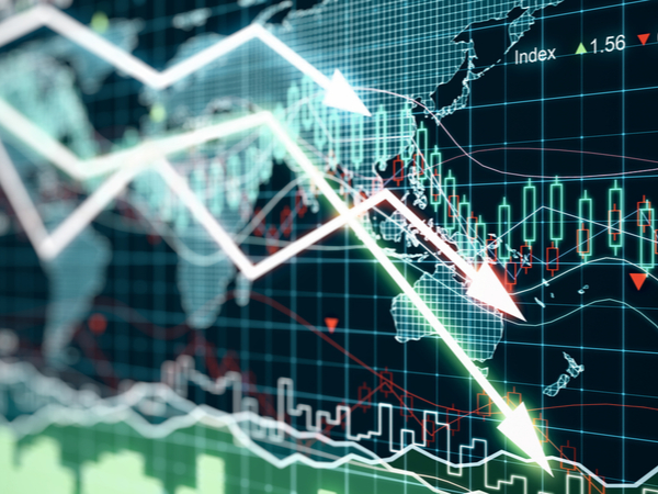 Financial index lines going down in front of a map of the world