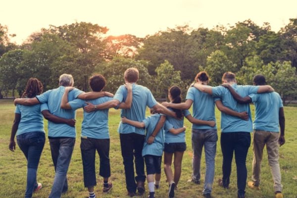 A line of people with their arms around each other walking in a field