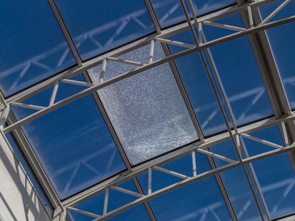 A glass ceiling with a broken window pane