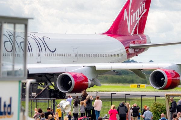 A Virgin Airlines airplane parked at a busy airport