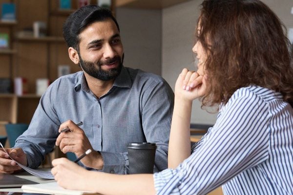 Two people talking at a desk