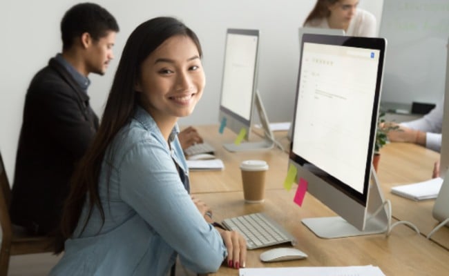 An employee sitting at a desk smiling at the camera