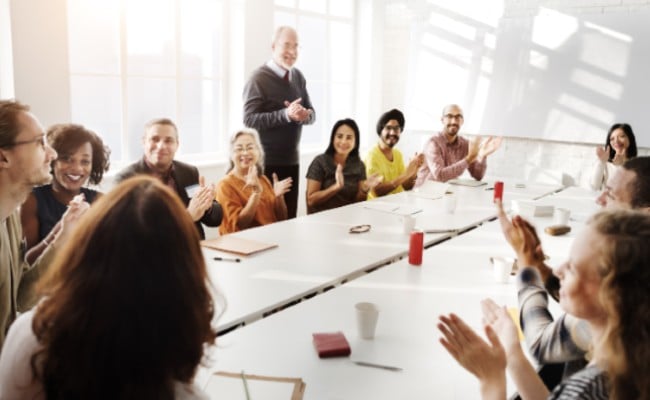 A group of people sitting around a large table in a boardroom