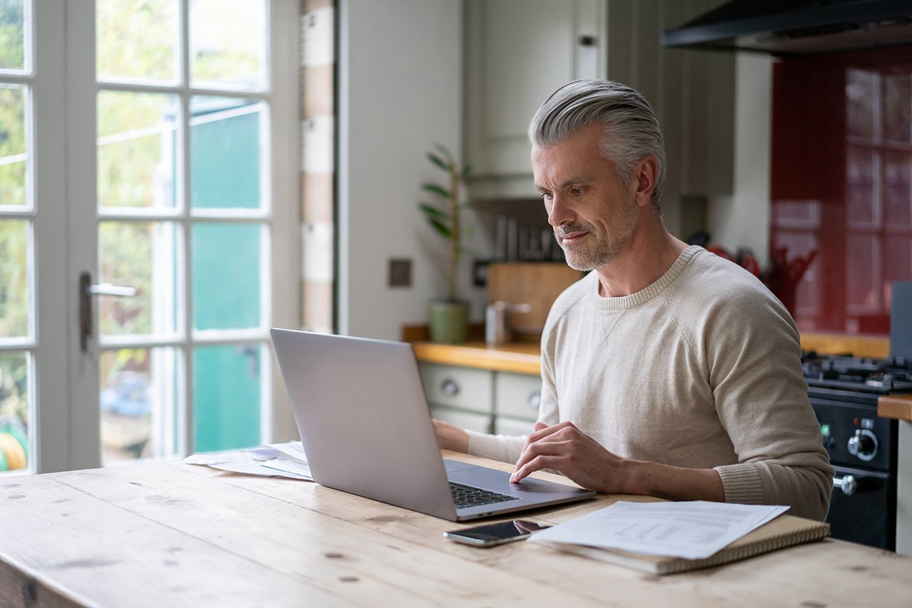 Portrait of an adult man working online at home on his laptop computer â lifestyle concepts