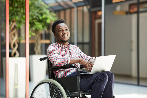 A man sitting in a wheelchair with a laptop