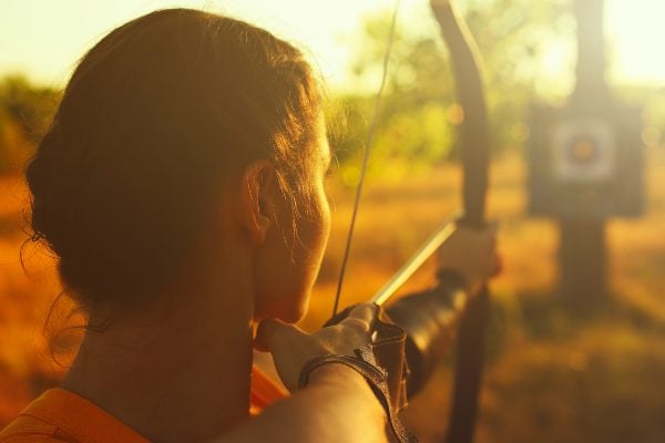 A person with a bow aiming an arrow at a target