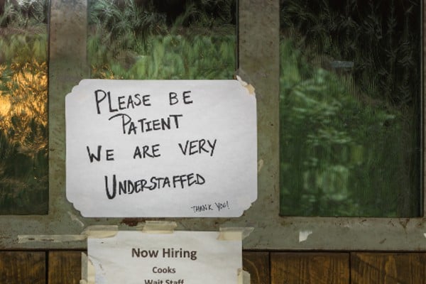 A now hiring sign in a shop window