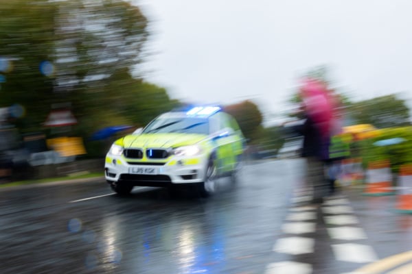 A police car with sirens on driving fast