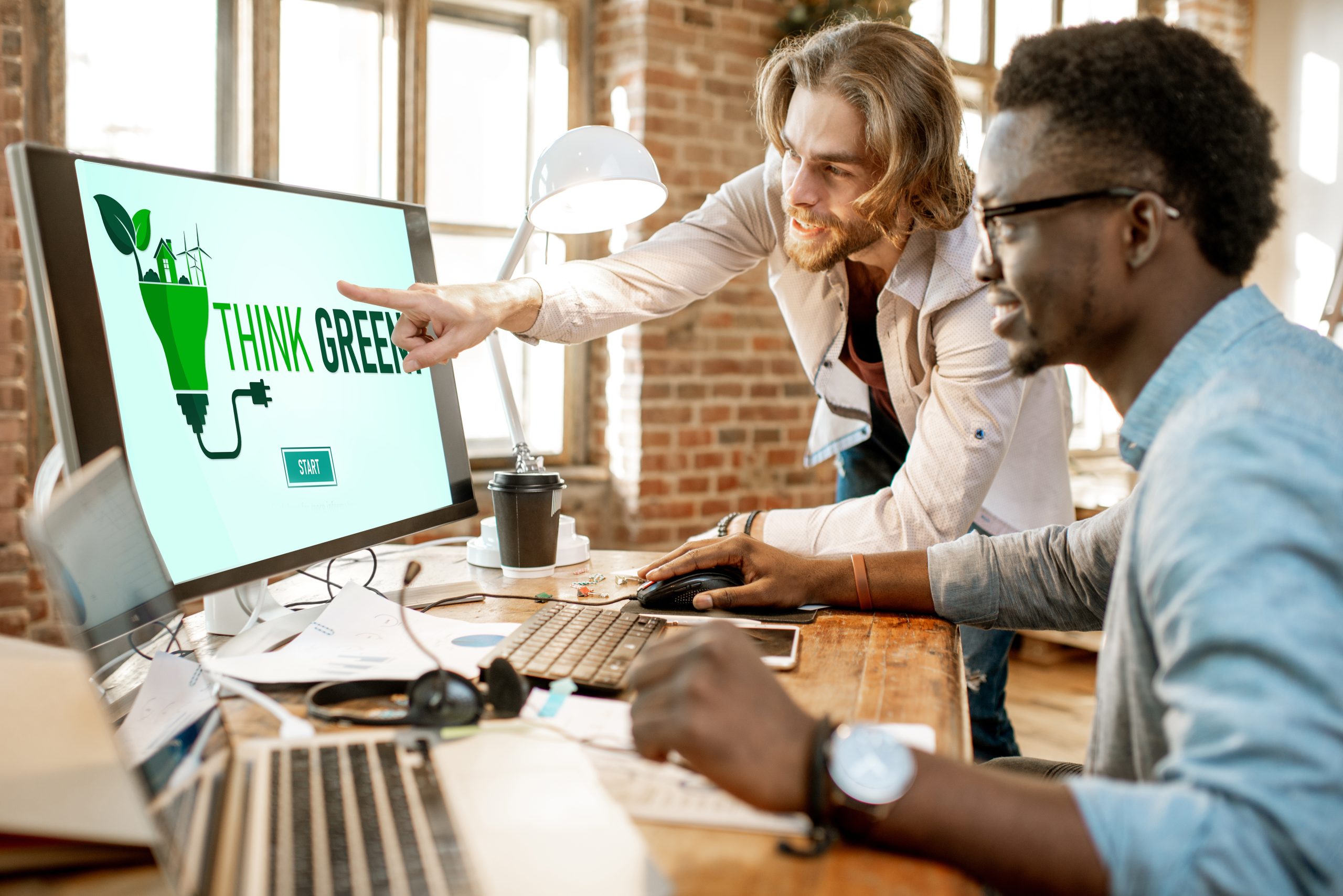 Two male coworkers working with analitycs in the beautiful office with brick wall on the background
