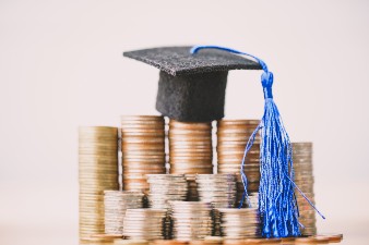 Graduation cap sat on top of some coins