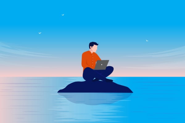 A man with a laptop sitting alone on a remote island in the ocean