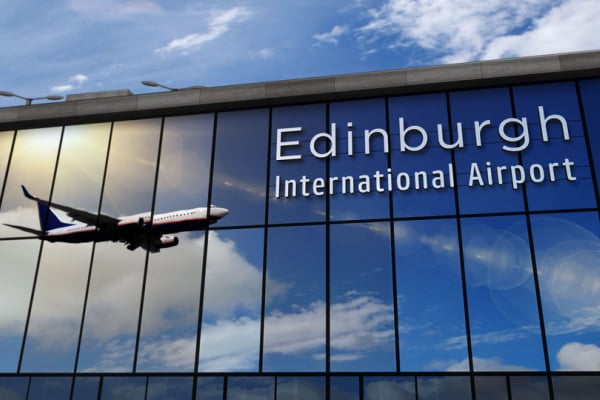 A picture of the Edinburgh International Airport building, with a plan flying across reflected
