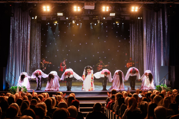 A group of actors in a theatre take a final bow to the audience