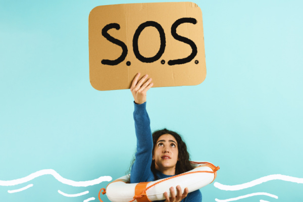 A person in the sea wearing a life ring holding an "SOS" sign