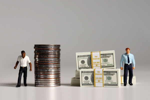 Two men of different ethnicities stood next to unequal piles of money