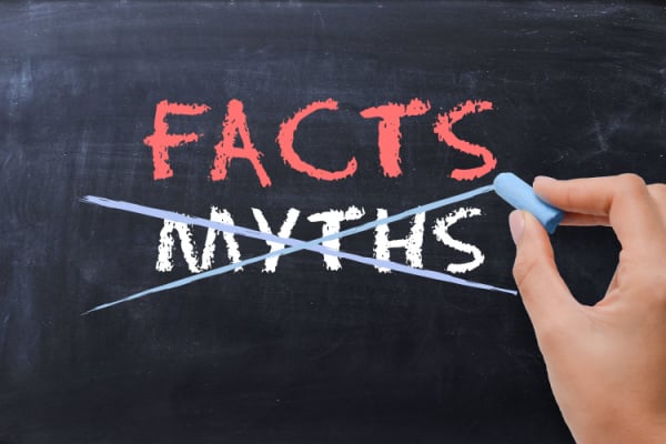 A person writing on a chalkboard with 'myths' crossed out, and 'facts' written above it