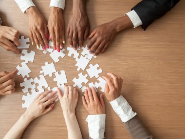 A multi-ethnic team assembling a jigsaw puzzle