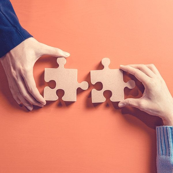 Hands putting together peices of a puzzle